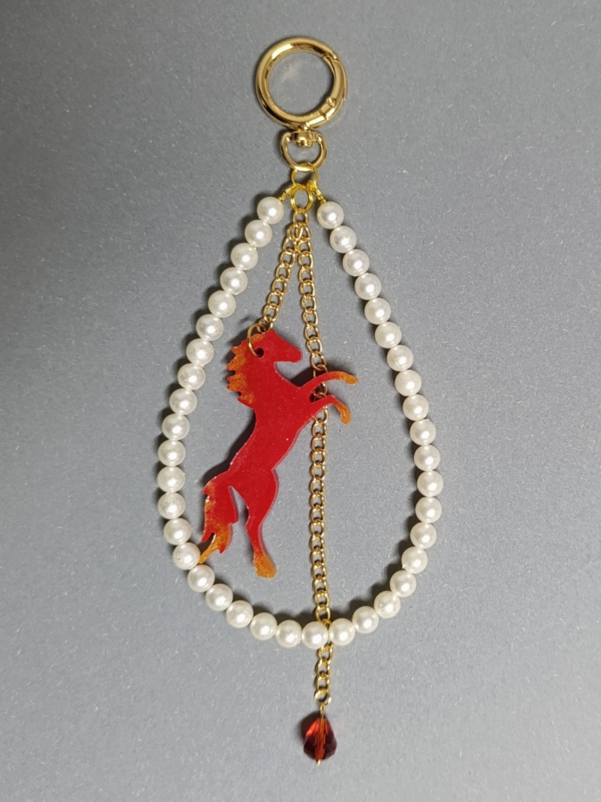 Elegancki brelok do torebki z perłami i czerwonym koniem