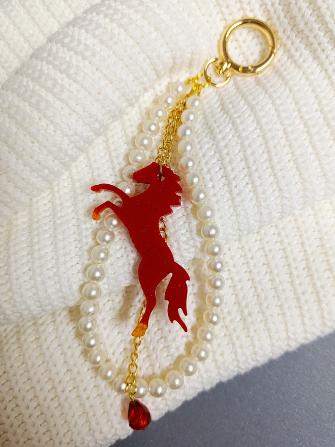 Elegancki brelok do torebki z perłami i czerwonym koniem