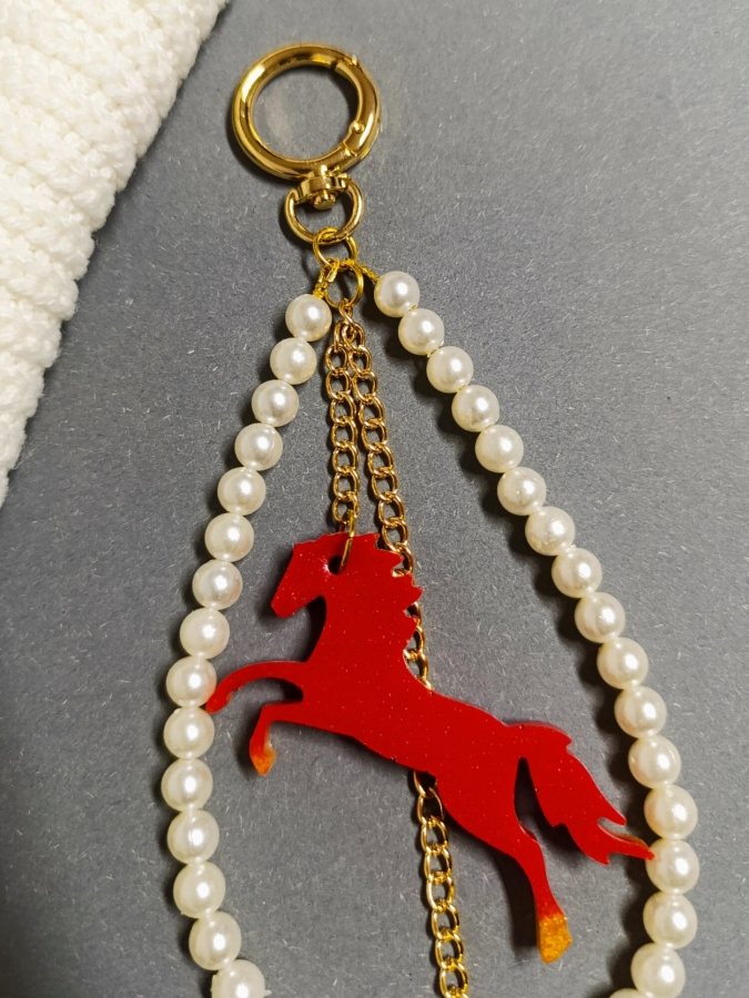 Elegancki brelok do torebki z perłami i czerwonym koniem